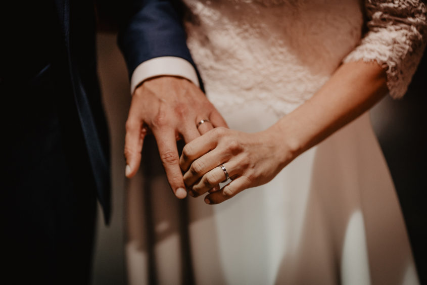 Gros plan, details des alliances, main dans la main, photographie de mariage d'A et M