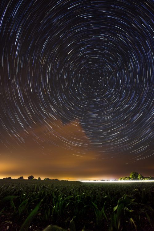 Circumpolaire (Port Marant, 17) L’étoile polaire est approximativement alignée sur l’axe de rotation de la terre, visible uniquement depuis l’hémisphère nord. De part son alignement et du point de vue de la Terre, nous avons l’impression que les autres étoiles tournent autour d’elle. On peut retranscrire se mouvement sur une photo par une pause longue, permettant de suivre la trajectoire des étoiles formant des trainées lumineuses concentrique autour de l’étoile polaire. Au dessus d’un champ de maïs, les nuages jaunes enrobent ses contours.